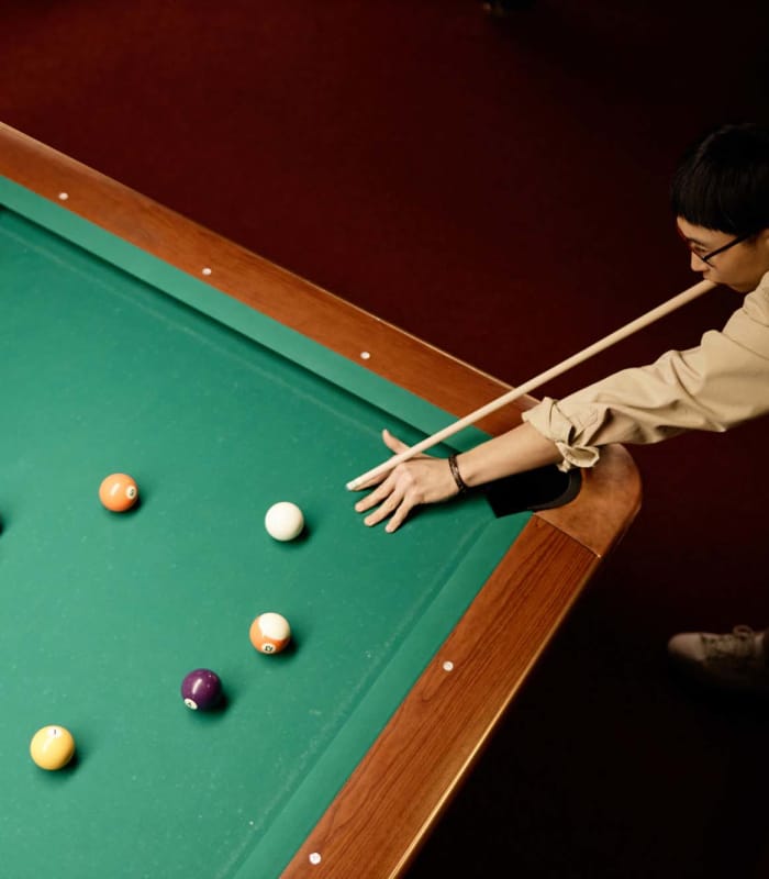 Person playing pool with colorful balls on a green felt table at Jordache Park Apartments in Spencerport, New York