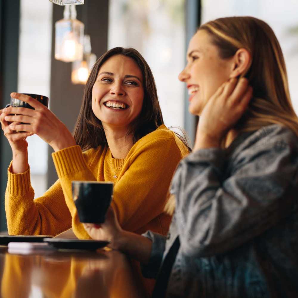 Resident friends sharing a laugh over a coffee at their favorite restaurant near Icon Apartments in San Antonio, Texas
