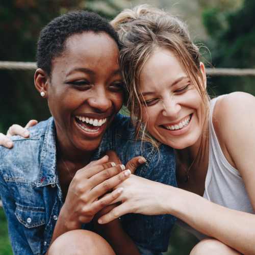 Two women laughing together outdoors near Penn Lincoln Apartments in Wilkinsburg, Pennsylvania