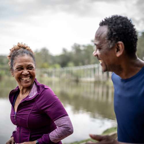 A happy older couple shares laughter by the tranquil water near EVOQ East Cobb in Marietta, Georgia