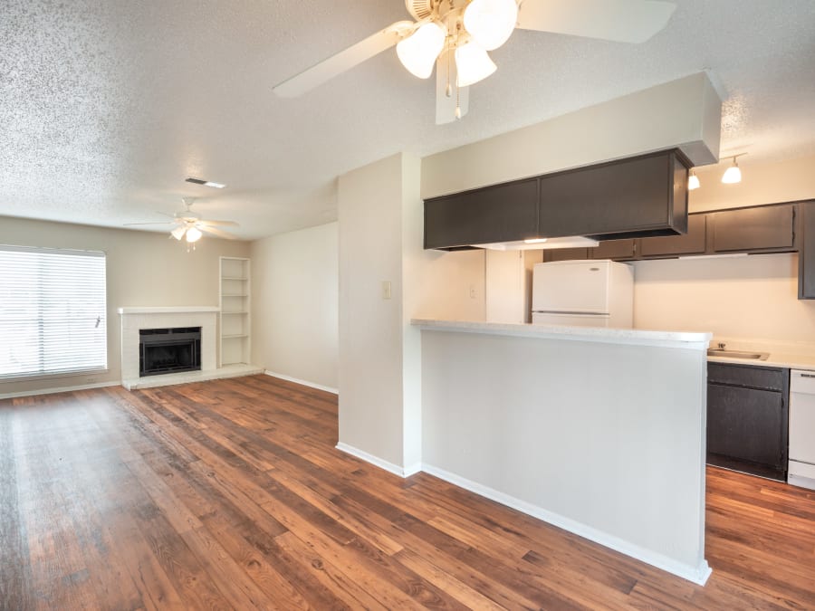 Beautiful hardwood floors in the kitchen and fireplace in the living area of a model home at The Madison in Dallas, Texas