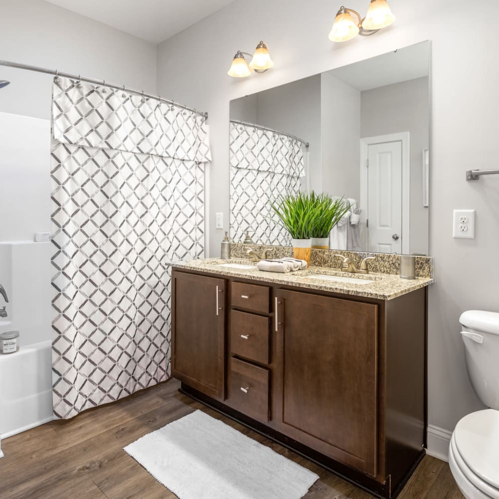 Dark wood cabinets and a full bathtub in an apartment bathroom at Retreat at the Park in Burlington, North Carolina