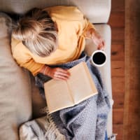 A woman reading a book on her couch at The Station at Clift Farm in Madison, Alabama