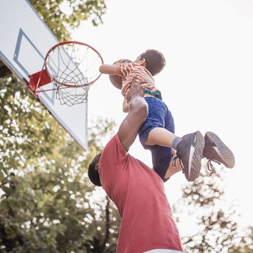 A resident helping his son dunk a basketball at Dahlgren Townhomes in Dahlgren, Virginia
