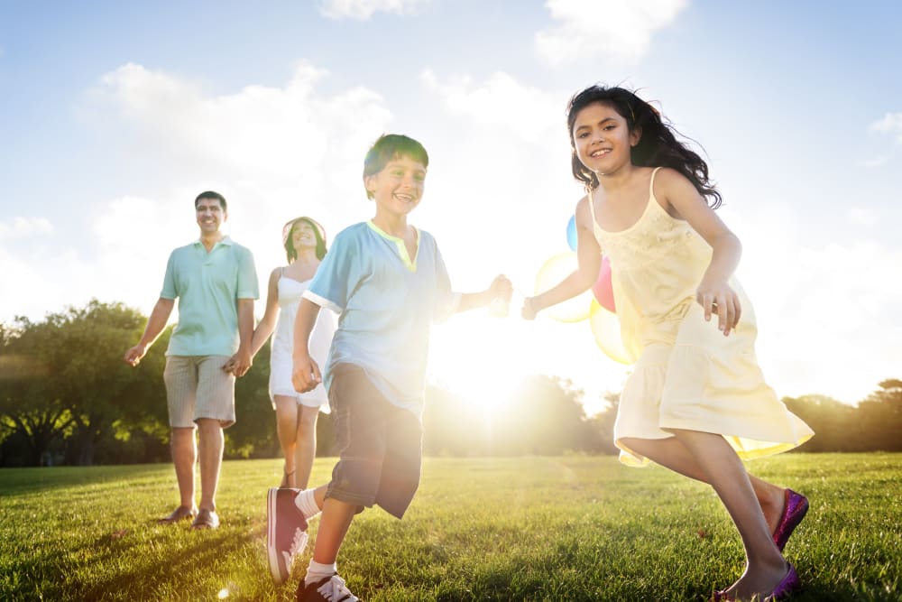 A resident family playing in the grass at Santa Fe Apartment Homes in Dallas, Texas