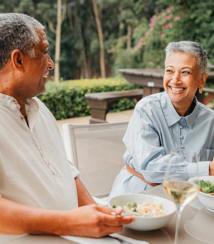 A happy senior couple dining together in a vibrant outdoor garden pavilion at EVOQ East Cobb in Marietta, Georgia