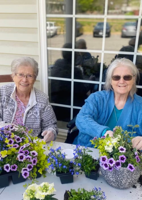 Residents smiling while planting flowers at English Meadows Prince William Campus in Manassas, Virginia