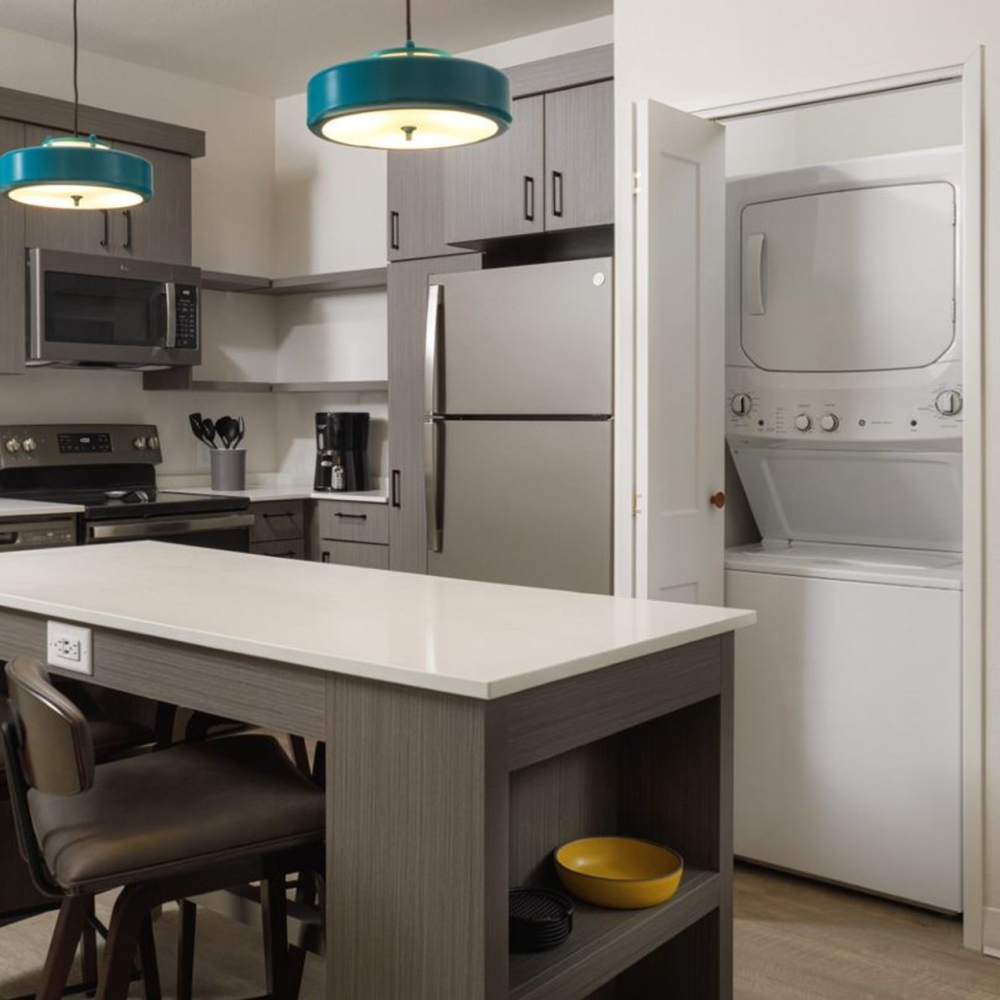 Kitchen with island, in-unit washer and dryer, and stainless steel appliances at Waterwalk Tucson in Tucson, Arizona