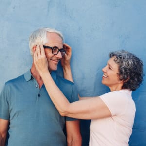 Resident couple standing against a blue wall outside at Sunstone Village in Denton, Texas