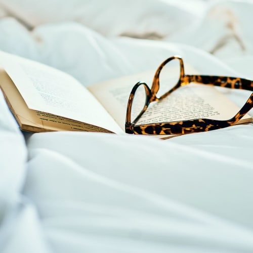 Book and glasses on bed at Meridian at Stanford Ranch in Rocklin, California