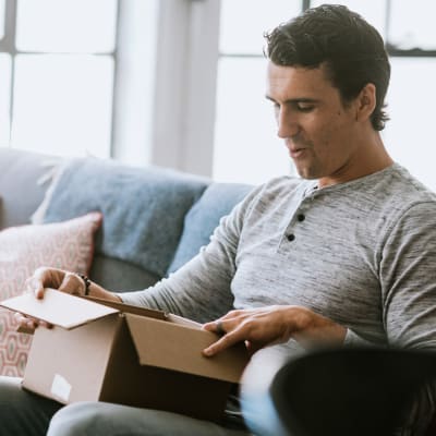 Man opening box on couch in Ocotillo Heights in Twentynine Palms, California