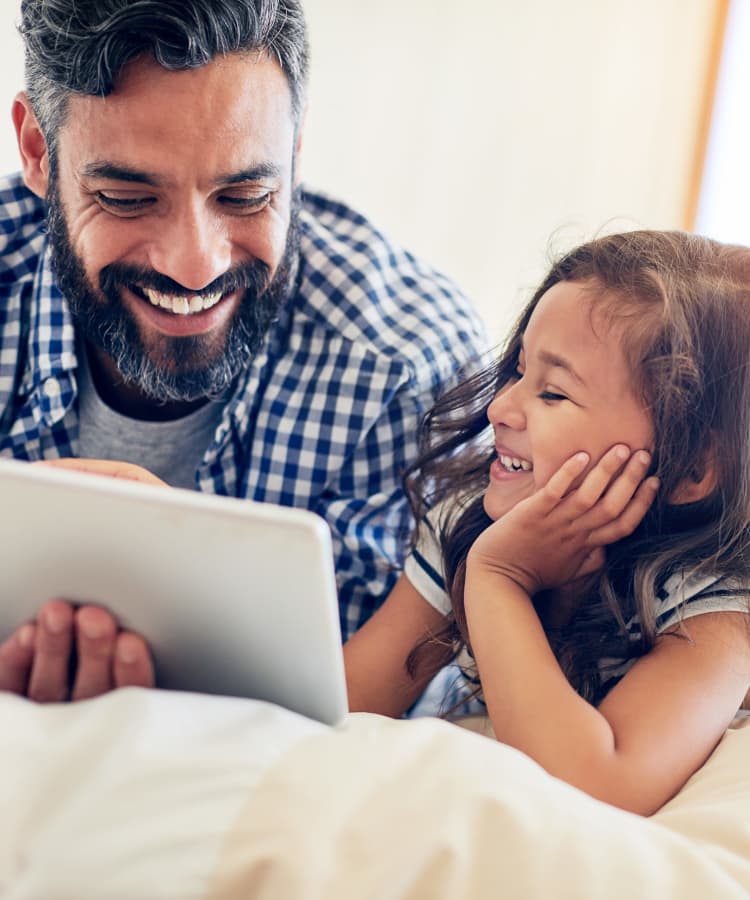 Father and daughter playing with a tablet at Haddon Knolls Apartments