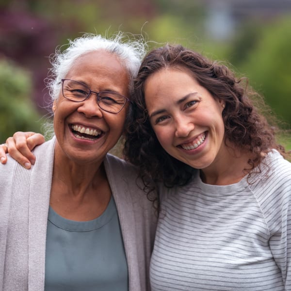 Resident and daughter hugging outdoors at Pacifica Senior Living Burlingame in Burlingame, California