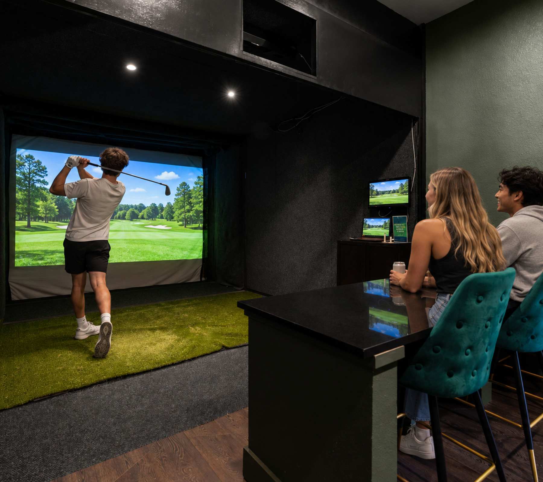 Group watching a friend swing at a golf simulator screen from a bar with teal stools at The Domain at Columbia in Columbia, Missouri