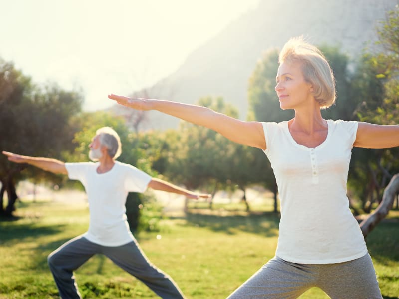 Two residents doing yoga outside on a sunny day at Citrus Place in Riverside, California