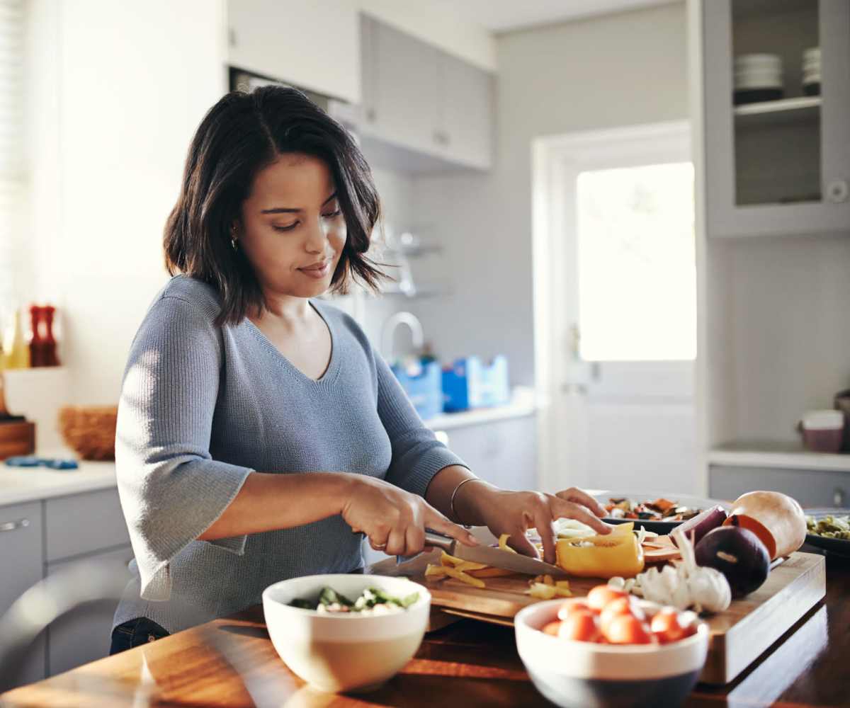 Resident woman chopping vegetables in her apartment kitchen at Annhurst Apartments in Gahanna, Ohio