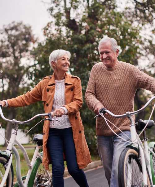 An elderly couple going for a walk with their bicycles at Athens Vista Senior Apartments in Los Angeles, California