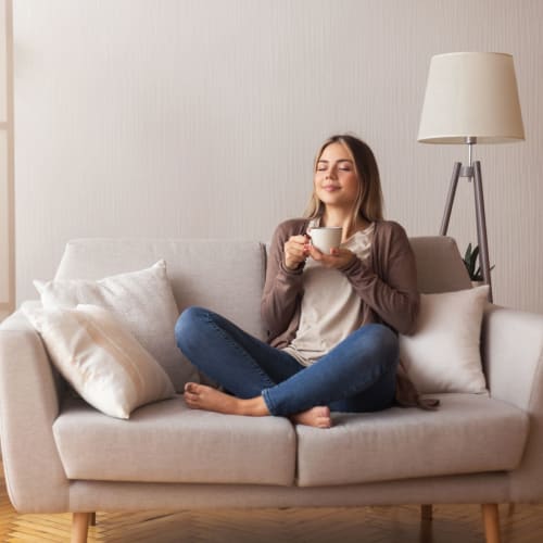 Woman on her couch enjoying coffee at Woodstream Townhomes in Rocklin, California