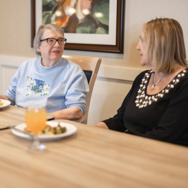 Two residents laughing together at a table at The Castlewood Senior Living in Nixa, Missouri