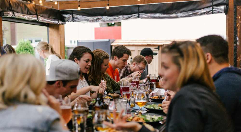 Residents enjoying the food and toasting their glasses on a patio near the Katy Trail near Remi in Dallas, Texas