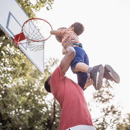A resident lifting his son to dunk a basketball at Chesterton Townhomes in San Diego, California