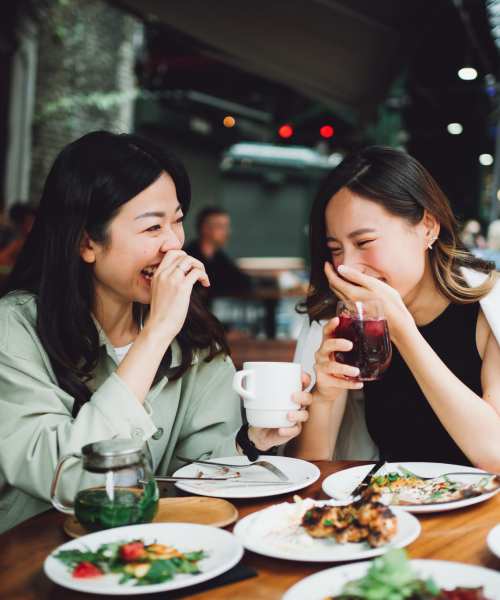 Two woman laughing at a table near East Boulevard Apartments in Rochester, New York