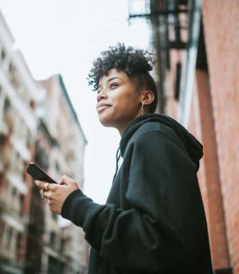 Resident holding a smartphone and looking neighborhood at 440 on Third Apartments in Baton Rouge, Louisiana