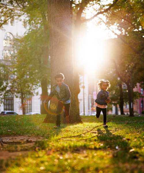 Kids enjoying a sunny outdoor lawn with greenery and walking paths at Granada Gardens Apartments in Warrensville Heights, Ohio