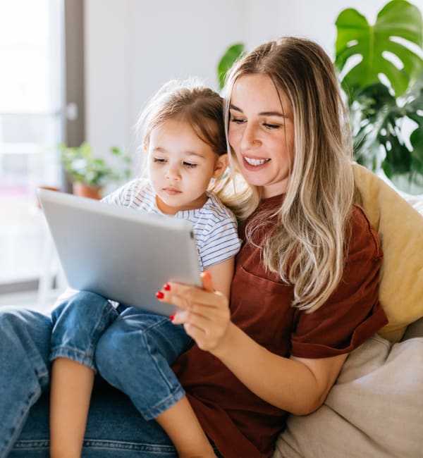 A woman with her young daughter on her lap looking at a tablet at The Courts of Avalon in Pikesville, Maryland