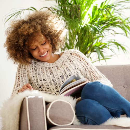 A happy resident reading a book at The Village at NTC in San Diego, California