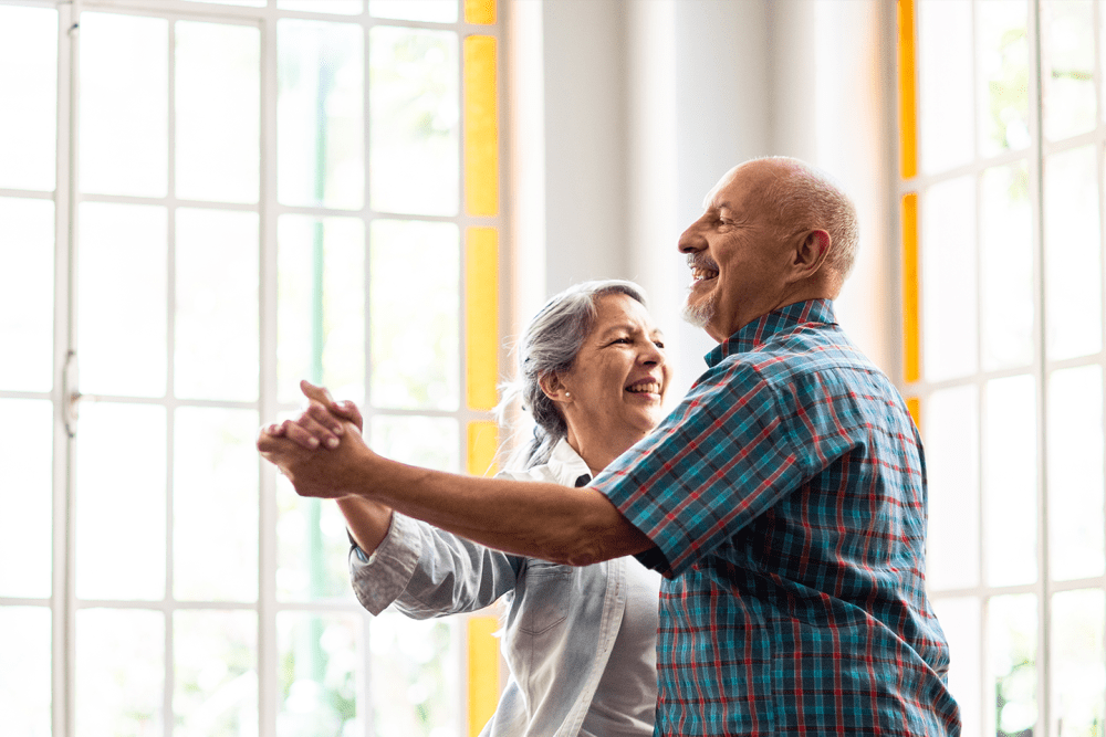 Two residents dancing in a brightly lit lounge at The Spring at Silverton in Fort Worth, Texas