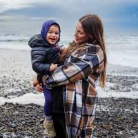 Woman holding smiling toddler on beach near Cape At Savona Apartments in Cape Coral, Florida
