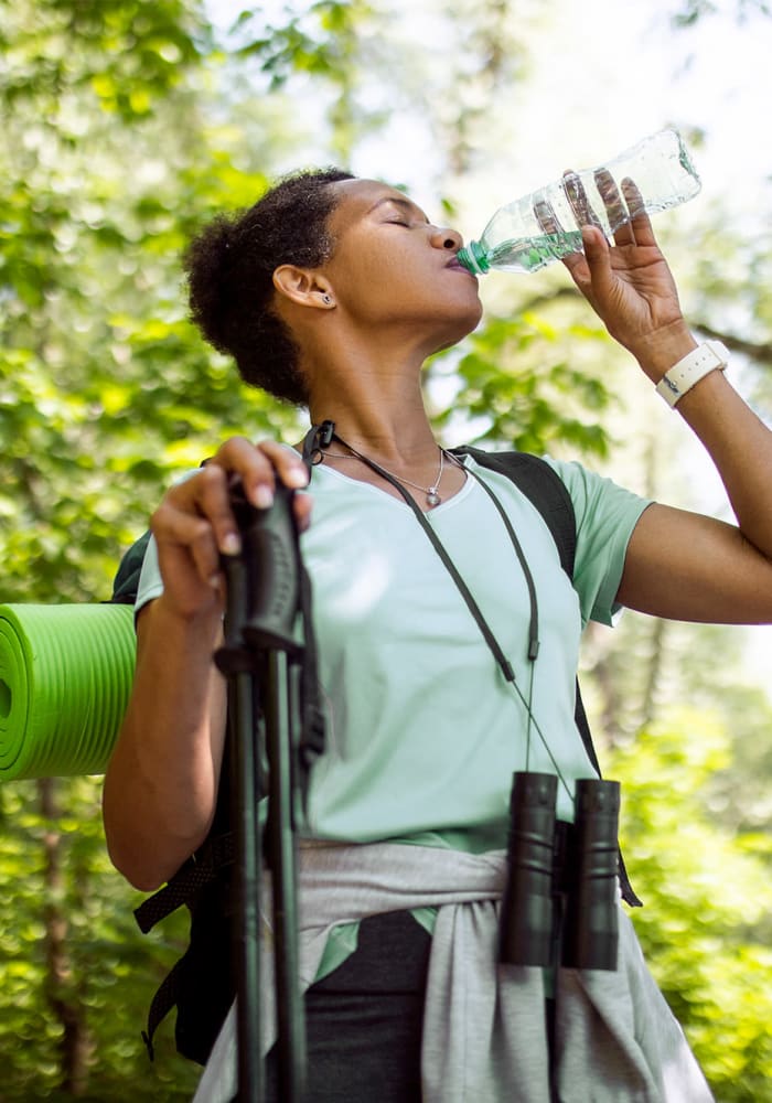 A woman drinking water while on a hike near Windsor Park in Woodbridge, Virginia