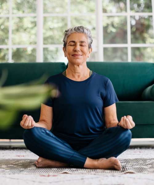 Resident doing yoga in her living room at Athens Vista Senior Apartments in Los Angeles, California