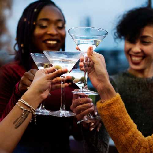 Hands holding cocktail glasses with olives near Avia Lofts at Maple Road in Amherst, New York