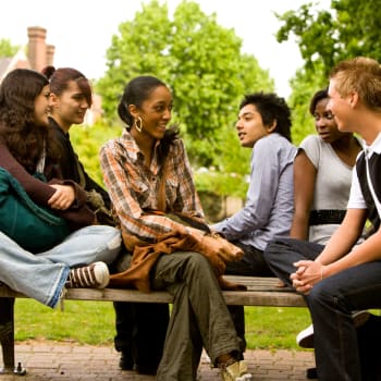 Friends chatting on a bench outside at Ashland Garden in San Lorenzo, California