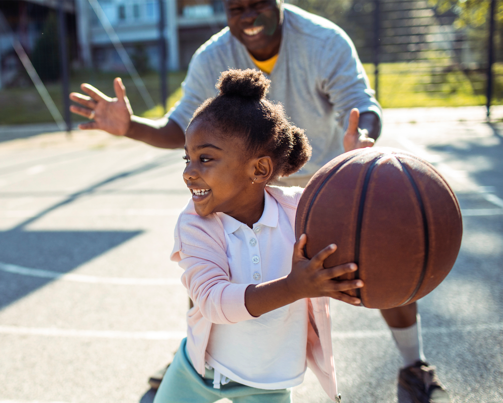 A resident playing basketball with his daughter at Aero Ridge in San Diego, California