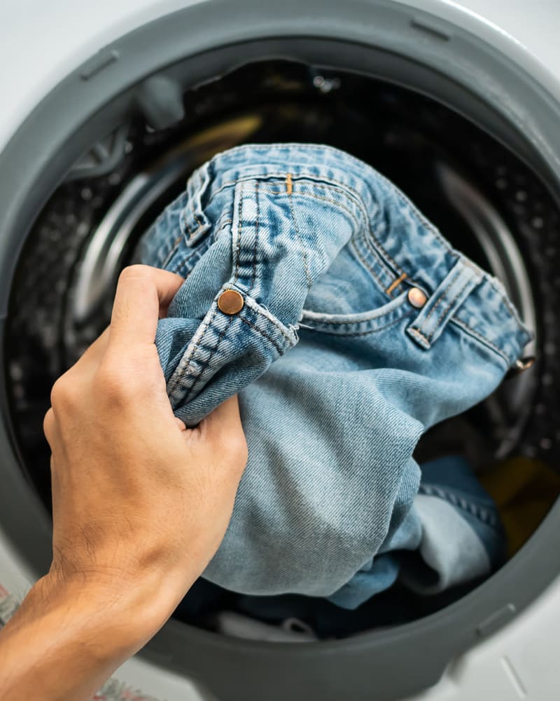 A resident doing laundry in an apartment at The Retreat in Santa Clarita, California
