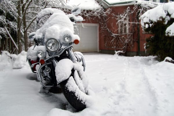 Motorcycle covered in snow outside of house