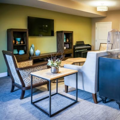 A modern community room with furniture and a piano at The Sanctuary at West St. Paul in West St. Paul, Minnesota