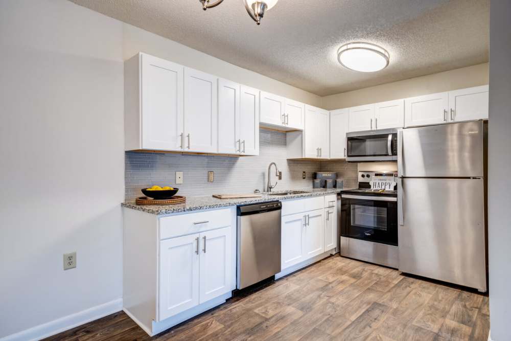 Upgraded kitchen with white cabinets, stainless appliances, and granite countertops