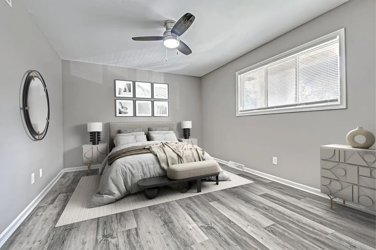 Spacious bedroom with a comfortable bed, large window and a ceiling fan at Woodside Village in Valparaiso, Indiana
