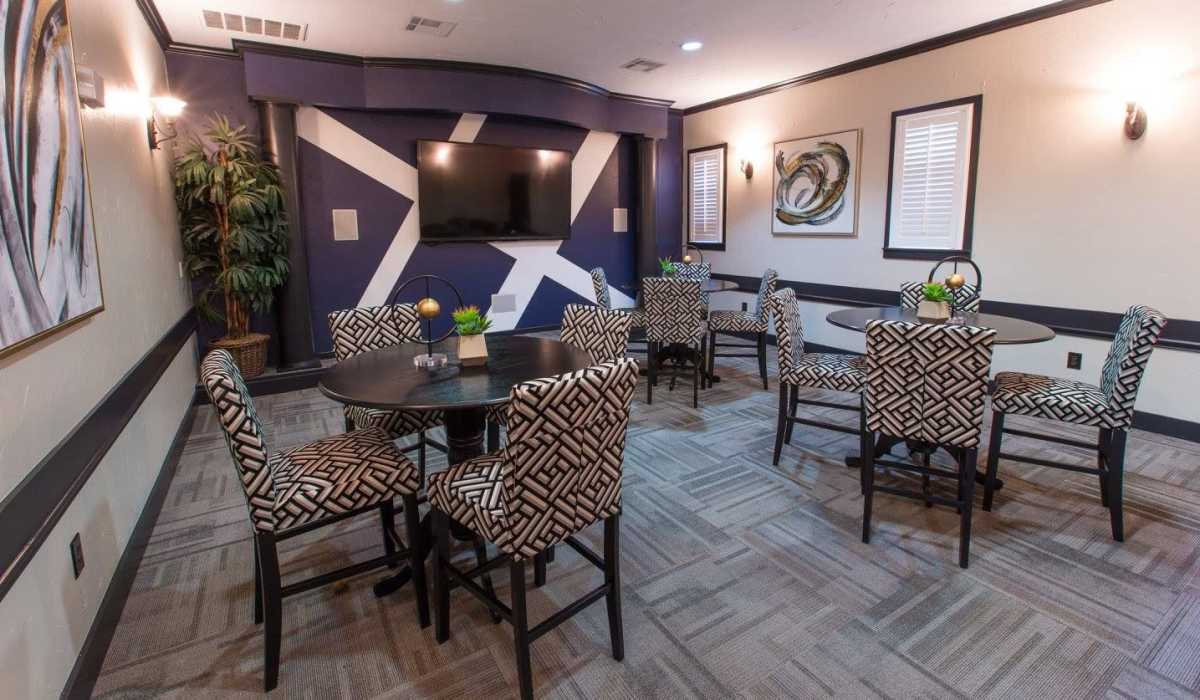 Resident seating area with chairs, tables and flat screen TV at Cobblestone Park in Manvel, Texas