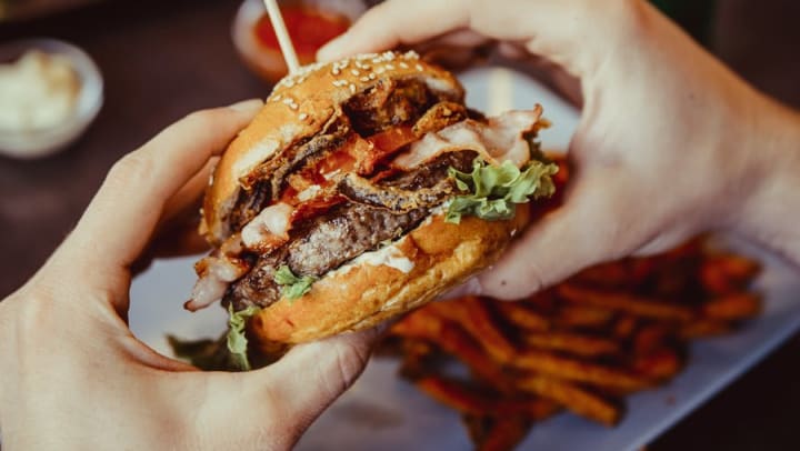 Customer about to bite into a hamburger at a restaurant near Olympus Corsair in San Diego, California