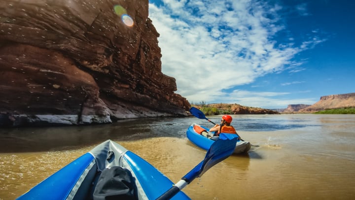View from perspective of a kayaker of another kayaker on the shore of a -river.