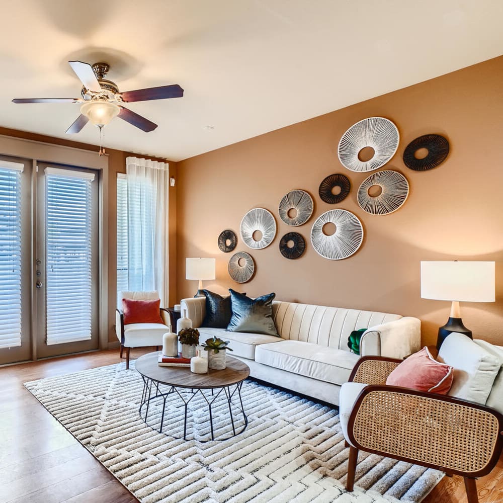 Model living room with a ceiling fan opening onto a private balcony at Imperial Lofts in Sugar Land, Texas