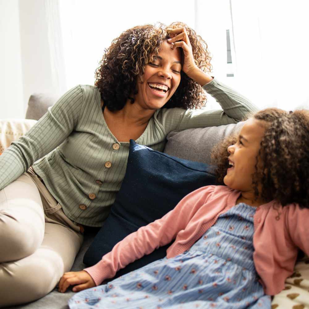 Resident and her daughter relaxing on their couch at Jasper Apartments in Swannanoa, North Carolina