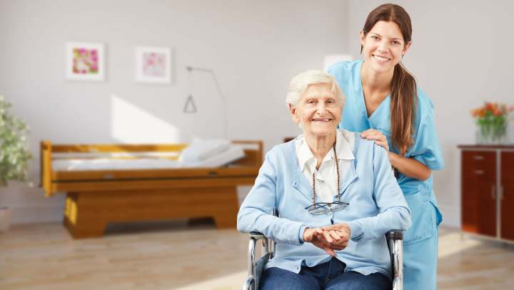 Resident and caregiver smiling in a bright room at The Landing at Watermere Frisco enjoying a moment of connection.