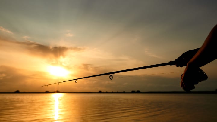 A person fishing as the sun sets.
