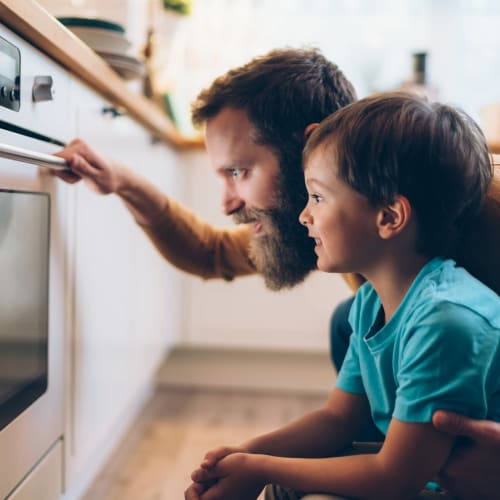 A father and son checking on food cooking in an oven at Mosby Steele Creek in Charlotte, North Carolina